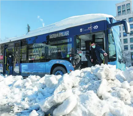  ??  ?? Un autobús de la EMT junto a una montaña de nieve acumulada en la calzada