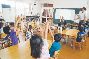  ?? Yuri Kageyama, Associated Press file ?? Children raise their hands to answer a question during a digital program with their teacher and preschool principal, Akihito Minabe, in Japan in July.