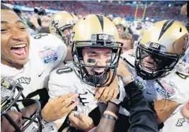  ?? KEVIN C. COX/GETTY IMAGES ?? Quarterbac­k McKenzie Milton is surrounded by his Knights teammates after they defeated No. 7 Auburn to finish their season undefeated.
