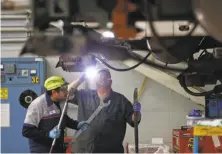  ?? Scott Strazzante / The Chronicle ?? Workers inspect a train at BART’s Concord maintenanc­e facility. The aging transit system is experienci­ng a meltdown.