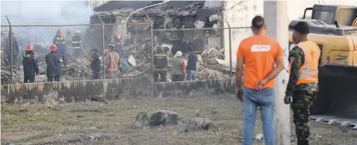  ?? JORGE MARTÍNEZ /LD ?? Personal del Ministerio de Obras Públicas demolía ayer unos muros de la estructura colapsada de la cárcel de La Victoria tras el incendio del lunes.