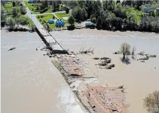  ?? NEIL BLAKE THE ASSOCIATED PRESS ?? People survey the flood damage on Wednesday to the Curtis Road Bridge in Edenville, Mich., over the Tittabawas­see River. The bridge sits just south of Wixom Lake, where two dams failed.