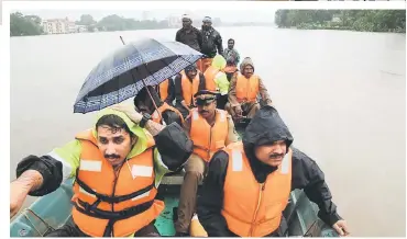  ?? — AFP photo ?? Indian fire and rescue personnel evacuate local residents in an boat flooded following monsoon rains at Aluva.