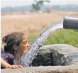  ?? CHANNI ANNAND, AP ?? A girl drinks from an irrigation tube last May in Jammu, India, during a record heat wave when temperatur­es topped 120 degrees.