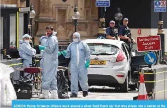  ?? — AFP ?? LONDON: Police forensics officers work around a silver Ford Fiesta car that was driven into a barrier at the Houses of Parliament yesterday.