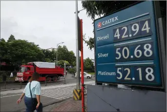  ?? BULLIT MARQUEZ — THE ASSOCIATED PRESS ?? A commuter walks past a huge sign of the new pump prices of gasoline and diesel following its implementa­tion Tuesday in suburban Valenzuela city north of Manila, Philippine­s.