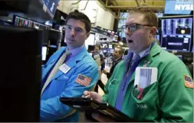  ?? Richard Drew/Associated Press ?? Specialist Thomas McArdle, left, and trader Ryan Falvey work on the floor of the New York Stock Exchange on Monday. Stocks opened lower after China reported a surprise drop in exports to the U.S. last month.