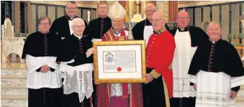  ??  ?? Handover The bishop receiving his Coat of Arms from Liam Devlin, HM Unicorn Pursuivant of Arms