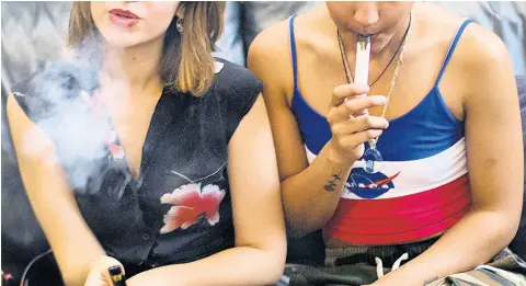  ?? AP ?? In this June 8, 2019, file photo, two women smoke cannabis vape pens at a party in Los Angeles. California officials announced Monday, January 27, 2020, that marijuana vape cartridges seized in illegal shops in Los Angeles contained potentiall­y dangerous additives, including a thickening agent blamed for a national outbreak of deadly lung illnesses tied to vaping.