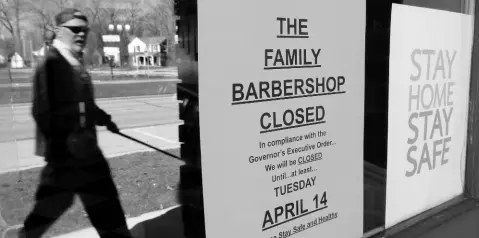  ??  ?? A pedestrian walks by a closed business, The Family Barbershop, in Grosse Pointe Woods, Michigan, on Thursday, April 2, 2020.