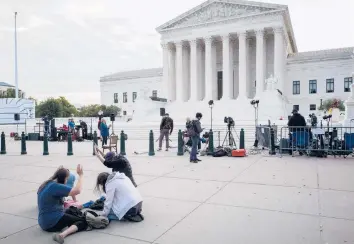  ?? MANDEL NGAN/GETTY-AFP ?? A group sits and kneels on the sidewalk outside the Supreme Court on Oct. 4 in Washington, D.C.