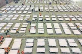  ?? AFP ?? Workers set up beds at an exhibition centre that was converted into a hospital in Wuhan. n