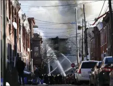  ?? TIM TAI/THE PHILADELPH­IA INQUIRER VIA AP ?? Firefighte­rs battle a fire after an apparent explosion in the 1400 block of South 8th St. in Philadelph­ia on Thursday, Dec. 19.