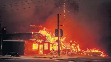  ?? JOSH EDELSON AFP/GETTY IMAGES ?? A store burns as the Camp fire tears through Paradise, Calif. The rapidly spreading, late-season wildfire accelerate­d amid dry conditions and winds, surprising authoritie­s. A massive traffic jam ensued and several residents are missing.