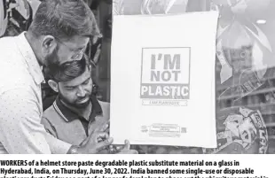  ?? Ap ?? Workers of a helmet store paste degradable plastic substitute material on a glass in Hyderabad, India, on Thursday, June 30, 2022. India banned some single-use or disposable plastic products Friday as a part of a longer federal plan to phase out the ubiquitous material in the nation of nearly 1.4 billion people.