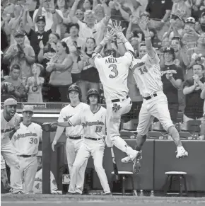  ?? GETTY IMAGES ?? Orlando Arcia of the Brewers leaps in the air as he celebrates his inside-the-park home run against the Padres during the third inning with Hernan Perez on Saturday at Miller Park.