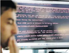  ?? VADIM GHIRDA / THE ASSOCIATED PRESS ?? Razvan Muresan, a Bitdefende­r public relations specialist in Bucharest, Romania, is backdroppe­d by a screenshot of the ransom message displayed on computers affected by the latest cyberattac­k this week.