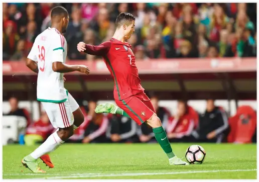  ??  ?? Portugal's forward Cristiano Ronaldo kicks the ball to score during the WC 2018 group B football qualifing match Portugal vs. Hungary at the Luz stadium in Lisbon on Sunday. (AFP)