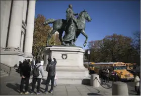  ?? MARY ALTAFFER — ASSOCIATED PRESS FILE ?? In a Nov. 17, 2017 photo, visitors to the American Museum of Natural History in New York look at a statue of Theodore Roosevelt, flanked by a Native American man and African American man.