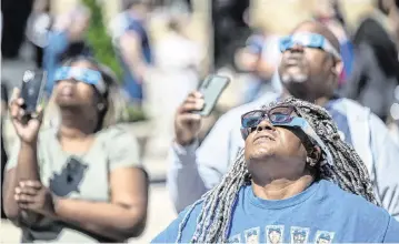  ?? TAMMY LJUNGBLAD Tljungblad@kcstar.com ?? Tiffany Rosada of Grandview, from left, Eugene and Bukeka Blakemore of Lenexa, watched the partial solar eclipse at Legends Outlets in Kansas City, Kansas.