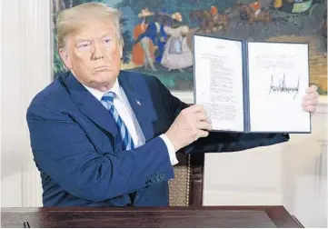  ?? EVAN VUCCI/AP ?? President Donald Trump signs a Presidenti­al Memorandum on the Iran nuclear deal on Tuesday.