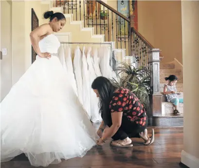  ?? Elizabeth Conley / Houston Chronicle ?? Monica Narvaez checks the bottom of Marcela Trejo’s wedding dress during a fitting on Friday in Tomball. Trejo was able to get her dress for her July 29 wedding out of Alfred Angelo’s store before it closed.