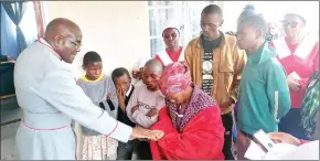  ?? ?? Some of the beneficiar­ies look on as Reverend Goodwill Masuku hands over the house keys to their grandmothe­r.