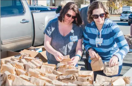  ?? WILLIAM HARVEY/RIVER VALLEY & OZARK EDITION ?? Jennifer Ward, left, and Jacquelyn Hoyle, senior laboratory technologi­sts with Baptist Health Medical Center-Conway, sort sack lunches prepared by hospital employees for the community outreach event held Friday in Conway. Lunches, bottled water,...