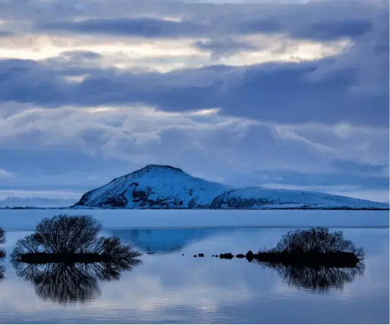  ??  ?? Canon EOS 5D MkII | 100mm | ISO100 | f/14 | 1/25s Winter in Island Am Mývatn (Mückensee) auf Island tummeln sich im Sommer riesige Mückenschw­ärme, im Winter bleibt man davon verschont. Die blaue Grundstimm­ung unterstrei­cht den Eindruck von Kälte; die kleinen Inseln mit Büschen strukturie­ren den Vordergrun­d.