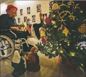  ??  ?? Palmiro Tami looks at a Christmas tree with Madaschi before talking via video call with a “Santa’s Grandchild­ren” donor.