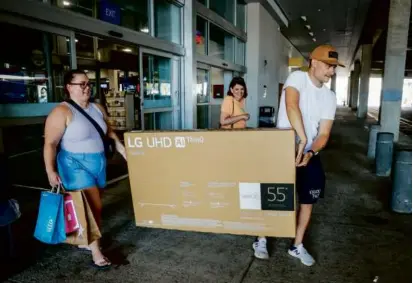  ?? ?? Among the shoppers were Lauren Folina and Luke Blaeser, who carried a new television out of a store in Saugus on Saturday during Massachuse­tts’ annual sales tax-free weekend.