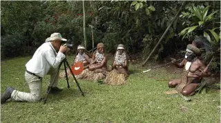  ??  ?? En la imagen de arriba, Salgado en 2010, tomando una fotografía a miembros de una tribu de Indonesia.
