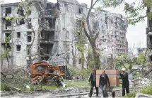  ?? Reuters-Yonhap ?? Local residents transport a box on a wheelbarro­w past a heavily damaged apartment building near Azovstal Iron and Steel Works, during the Ukraine-Russia conflict in the southern port city of Mariupol, Ukraine, Sunday.