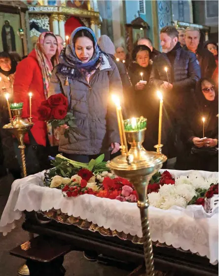  ?? ?? Grieving parents: Alexei Navalny’s father Anatoly and mother Lyudmila (circled) sit by his open coffin at the Church of the Icon of the Mother of God Soothes My Sorrows yesterday, surrounded by supporters with candles