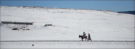  ?? (AP/Mosa’ab Elshamy) ?? A family crosses a road Dec. 4 amidst the snow to collect water in the Amazigh Timahdite village in the Middle Atlas, near Azrou, Morocco.