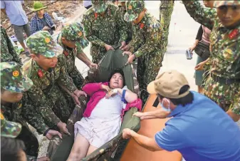  ?? Manan Vatsyayann­a / AFP / Getty Images ?? Soldiers rescue a woman from Typhoon Molave in Vietnam’s Quang Nam province. The storm set off landslides, blew off roofs of about 56,000 homes and caused a huge blackout.
