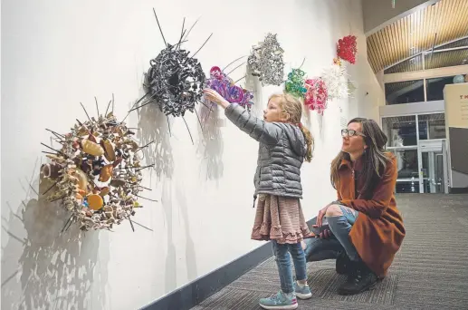  ?? Lauren Click, provided by the Dairy Arts Center ?? Elizabeth Morisette’s hanging plastic baskets are constructe­d of thousands of tiny, children’s toys.