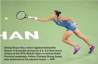 ??  ?? Zhang Shuai hits a return against Samantha Stosur of Australia during her 6-2, 6-2 first-round victory at the WTA Wuhan Open in central Hubei Province yesterday. Fellow Chinese Zheng Saisai also advanced to the second round. — AFP