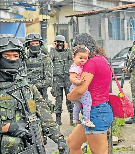  ??  ?? LA VIDA EN VERDE OLIVA. El Ejército brasileño custodia los accesos a las favelas de Río de Janeiro que las autoriddad­es consideran como más peligrosas.