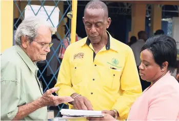  ?? CHRISTOPHE­R SERJU PHOTO ?? Hugh Lyon (left), the longest-serving director on the Jamaica Agricultur­al Society board of directors, gets assistance from Glendon Harris and Andrea Brown in checking for his name on the list of eligible voters. The 88-year-old, who has served as a director for 30 years, was denied the opportunit­y to vote because his name was not on the list of electors.