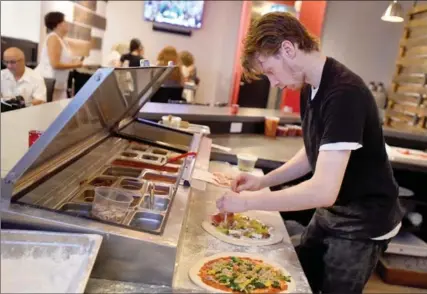  ??  ?? Mike Royston making pizzas at Sasso. Owner Mark Farrugia said it was challengin­g when they opened, “making food from scratch, using local suppliers.”