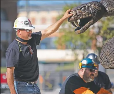  ?? (Tallahasse­e Democrat/Alicia Devine) ?? Brad Cooley Jr. steadies his large bronze rattle snake sculpture as a work crew prepares to install the piece of art in front of the Center for Access and Student Success Building at Florida A&M University in Tallahasse­e.