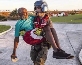  ?? AL DIAZ adiaz@miamiheral­d.com ?? A U.S. Coast Guard member carries a man out of a Marsh Harbour medical center on Friday.