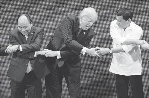  ?? JIM WATSON / AFP / GETTY IMAGES ?? Vietnam Prime Minister Nguyen Xuan Phuc, left, U.S. President Donald Trump and Philippine­s President Rodrigo Duterte join hands during the 31st Associatio­n of South East Asian Nations (ASEAN) Summit in Manila Monday. World leaders are in the...