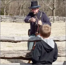  ?? TIMES photograph by Annette Beard ?? Nathan King, 6, of Pea Ridge, listens carefully as a Union re-enactor explains that children his age worked in factories rolling papers filled with gunpowder for Union troops. The scene was part of the reenactmen­t at the 153rd anniversar­y of the Battle...