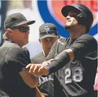  ?? Andy Cross, The Denver Post ?? Colorado’s Nolan Arenado grimaces after having a wrap applied to his left arm by trainer Keith Dugger, left, after Arenado was hit by hit by a pitch.