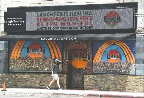  ??  ?? A pedestrian walks April 20 underneath a marquee advertisin­g a “Laughter is Healing” stand-up comedy livestream event at the Laugh Factory. (AP Photo/Chris Pizzello)