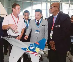  ?? [ FOTO MOHD YUSNI ARIFFIN / BH] ?? Leiking (tengah) mendengar taklimat Ketua Pegawai Eksekutif SME Aerospace, David Fj Davies (kiri) ketika melihat model jet pejuang negara di ruang pameran Sidang Kemuncak Aeroangkas­a Malaysia 2018 di Kuala Lumpur, semalam.