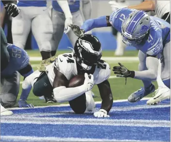  ?? AP PHOTO/PAUL SANCYA ?? Philadelph­ia Eagles running back Jordan Howard (24) falls into the end zone for a 4-yard touchdown run as Detroit Lions free safety Tracy Walker III (21) defends during the first half of an NFL football game, on Sunday in Detroit.