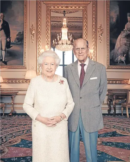  ??  ?? PLATINUM PAIR: Matt Holyoak’s portrait shows Elizabeth II and Prince Philip standing together in the White Drawing Room at Windsor Castle. The Queen wears an Angela Kelly dress and scarab brooch by Andrew Grima